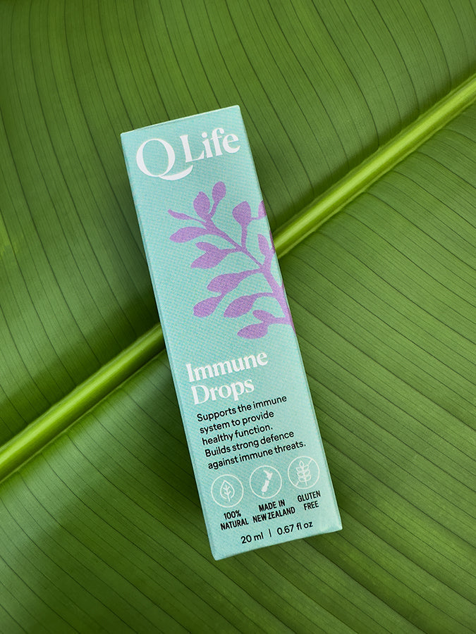 Q Life Immune Drops box on a green leaf, highlighting the product's natural ingredients.