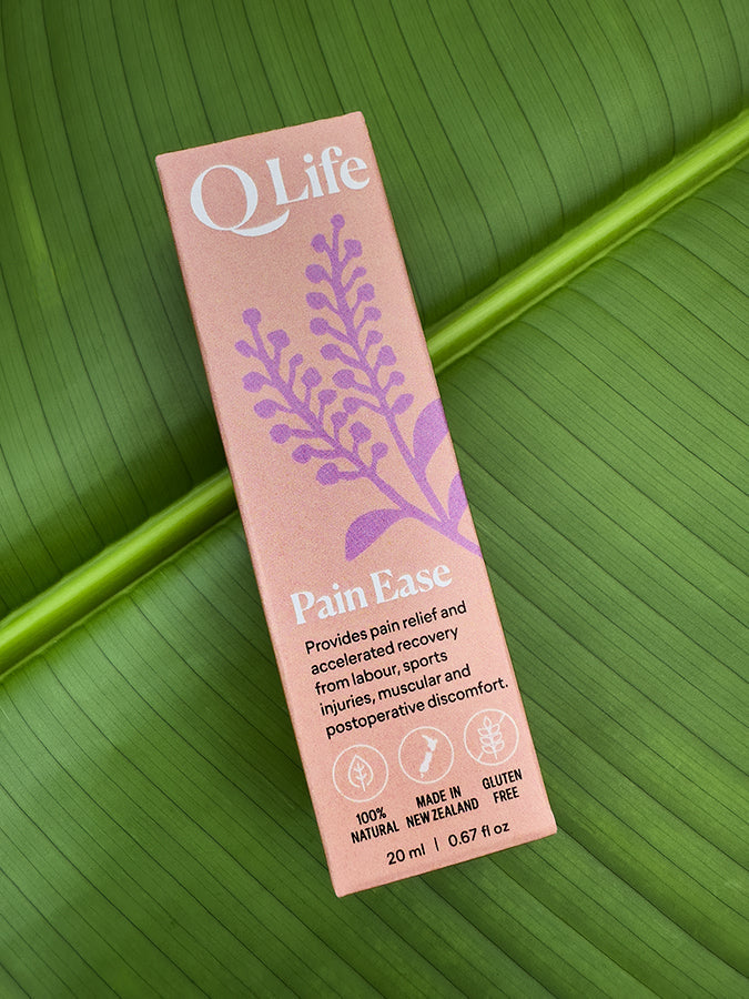 QLife Pain Ease box on a green leaf, highlighting the product's natural ingredients.
