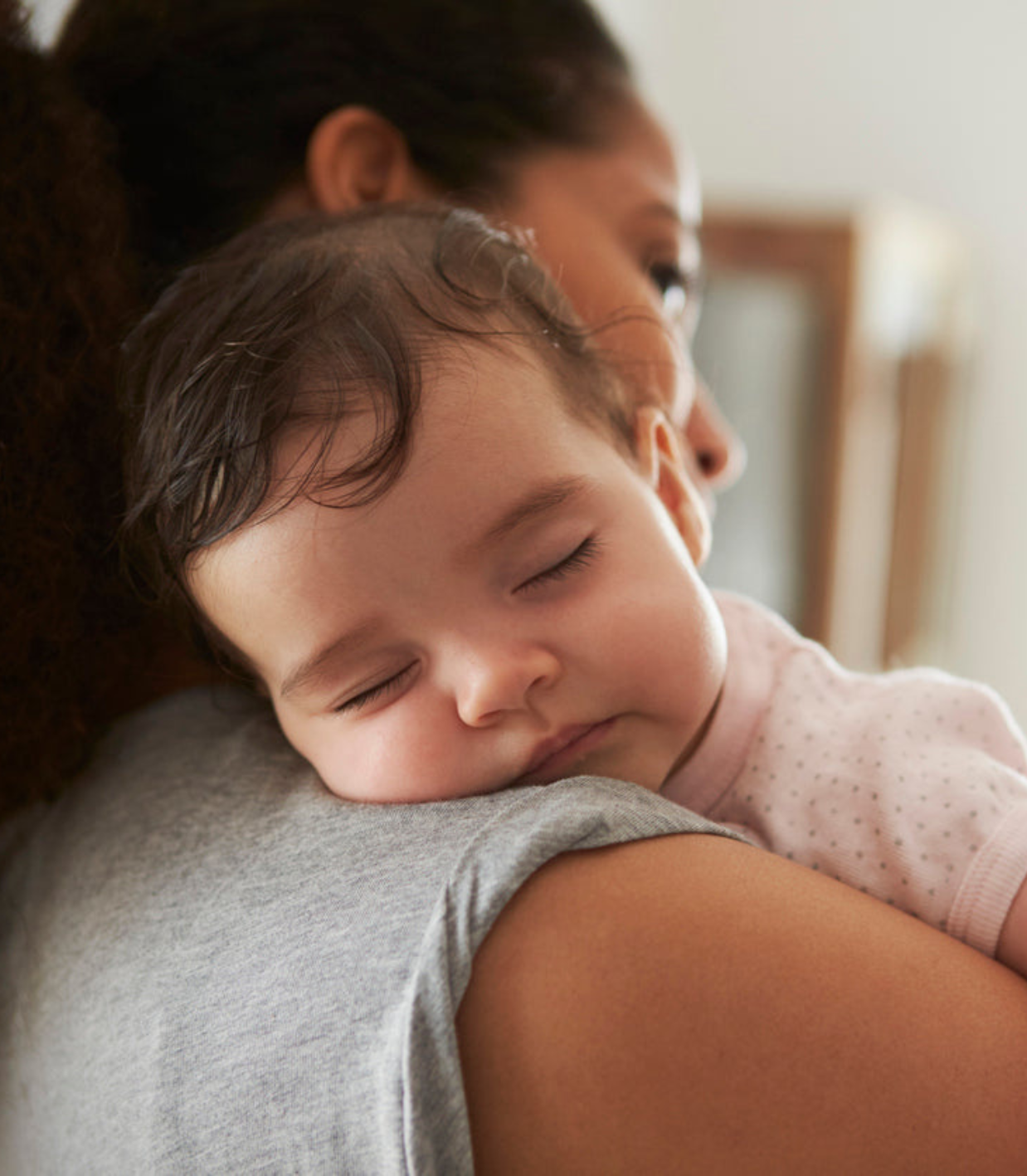 A baby sleeping peacefully being held by an adult